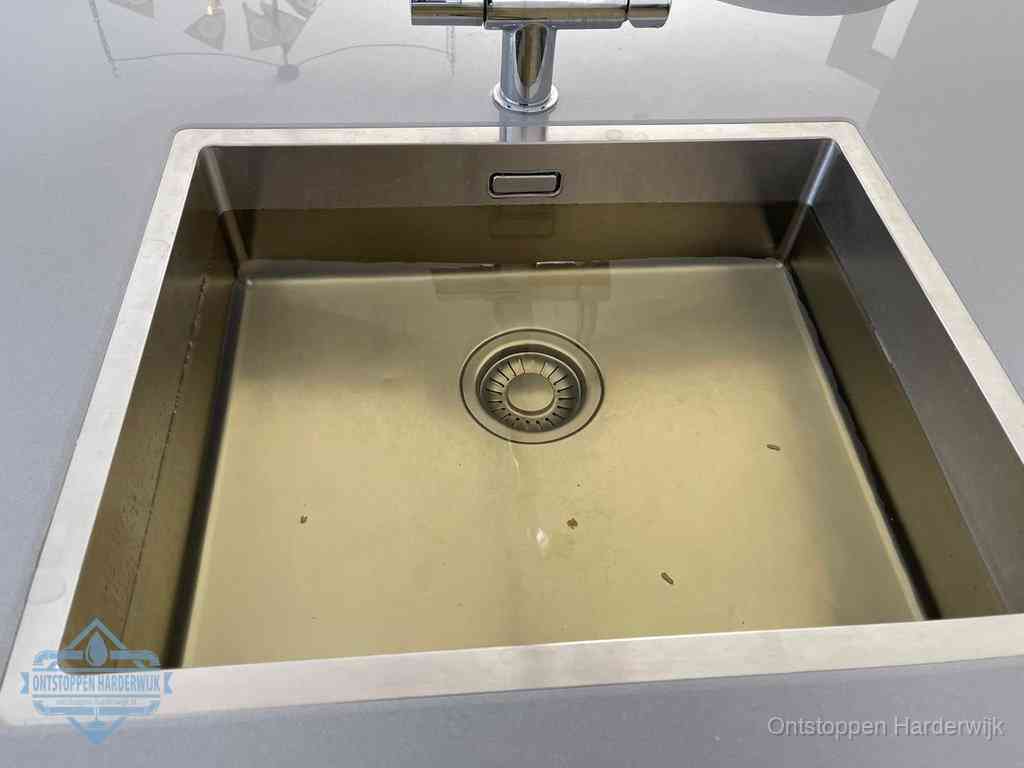 Stilstaand water in een rvs spoelbak dat niet wegloopt, een duidelijk signaal van een gootsteenverstopping in Harderwijk