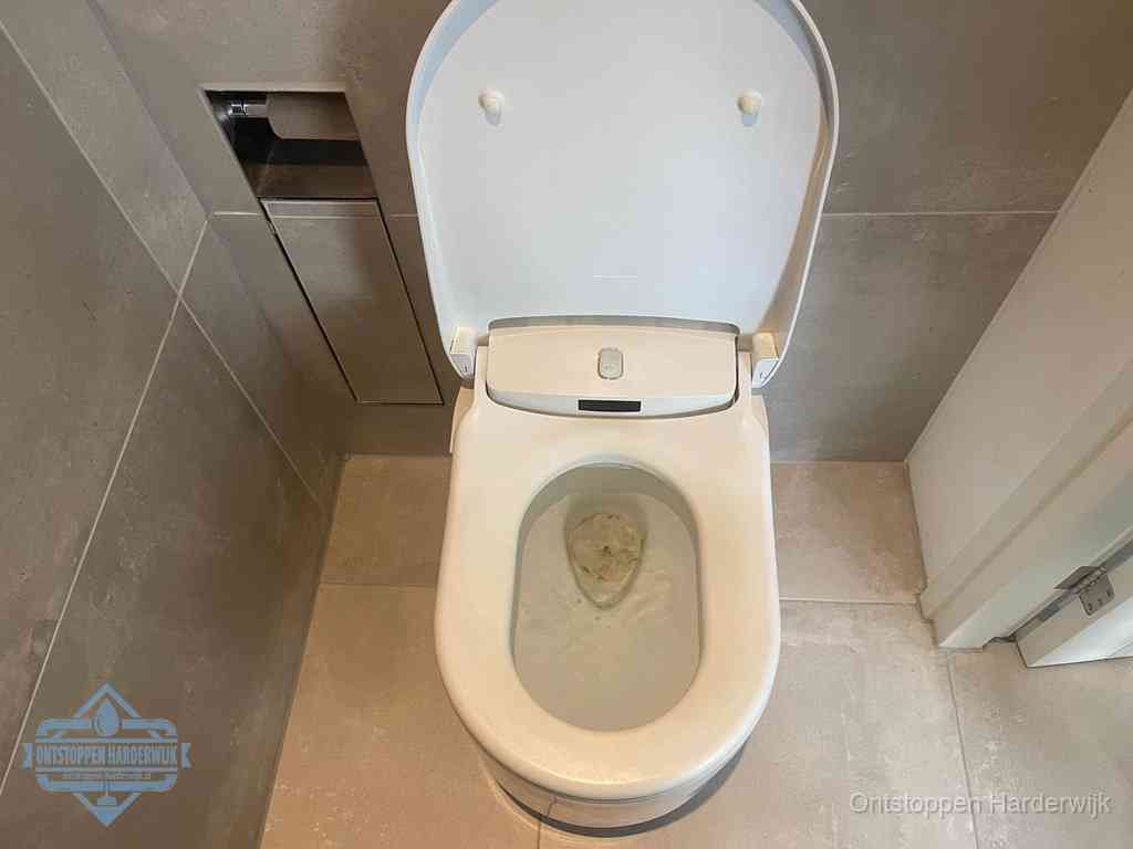 Een wit hangtoilet waarin een prop wc-papier op het water blijft drijven, een duidelijk signaal van een verstopte wc in Harderwijk