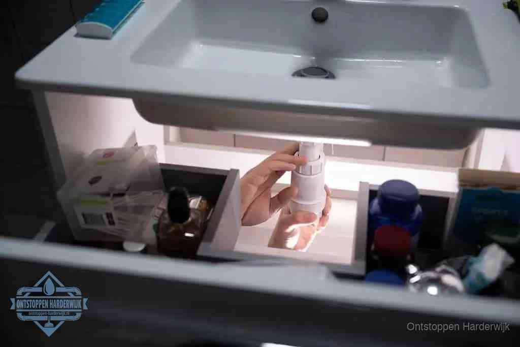 Een pompfles met zeep boven een wastafel in de toiletruimte, de warm water en afwasmiddel-methode om de wc te ontstoppen in Harderwijk