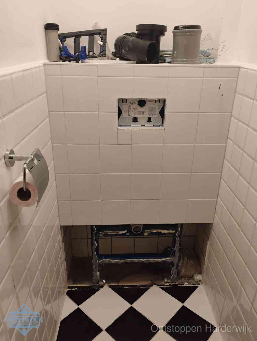 Een toiletruimte waar het hangtoilet en de inbouwreservoir-onderdelen zijn vrijgelegd voor onderhoud, periodiek nazicht voorkomt een wc-verstopping in Harderwijk